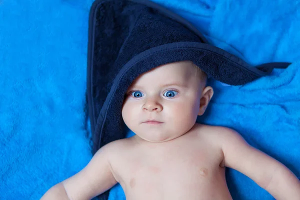 Menino menino pequeno contra a toalha de banho azul — Fotografia de Stock