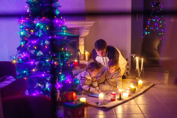 Junger Vater und seine kleinen Kinder sitzen am offenen Kamin auf dem — Stockfoto