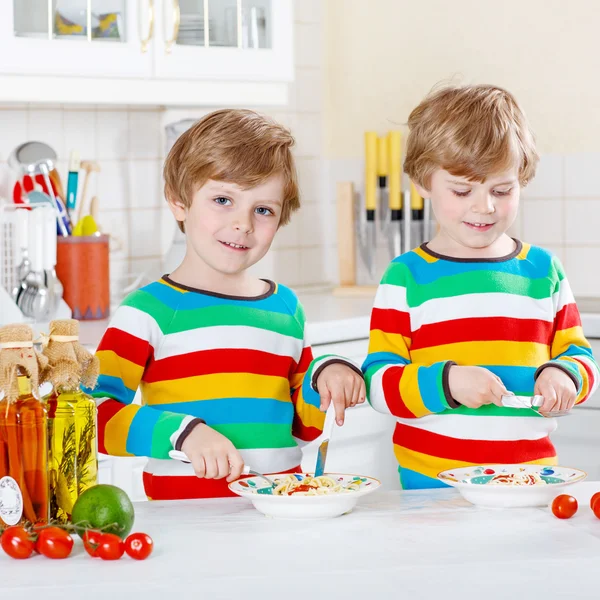 Dos niños comiendo espaguetis en la cocina doméstica . —  Fotos de Stock