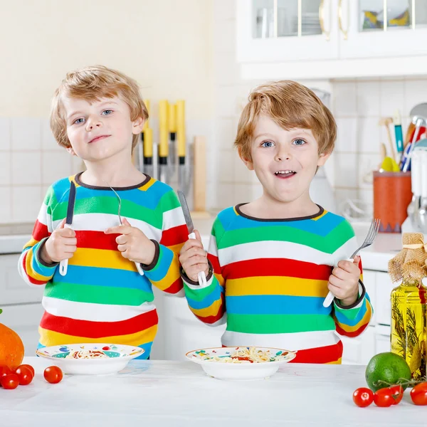 İki küçük çocuklar yerli mutfakta spagetti yiyen çocuk. — Stok fotoğraf