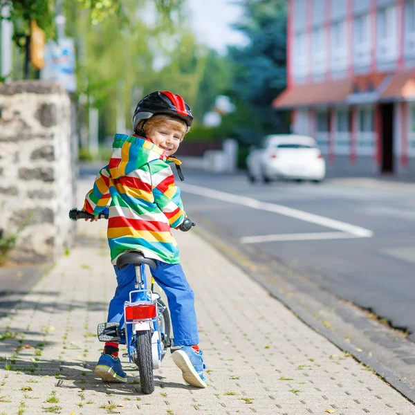 Niño en casco montando su primera bicicleta, al aire libre — Foto de Stock