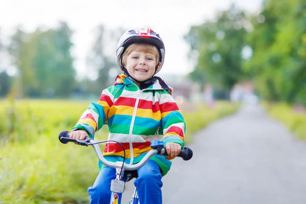 Enfant en casque chevauchant son premier vélo, à l'extérieur — Photo
