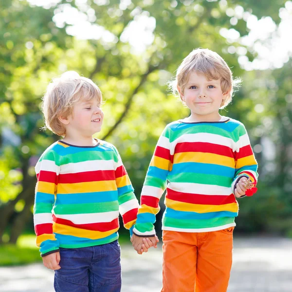 Két kis testvérek gyermekek színes ruhák séta kéz én — Stock Fotó