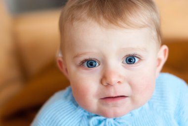 Baby with blue eyes looking at camera, indoors