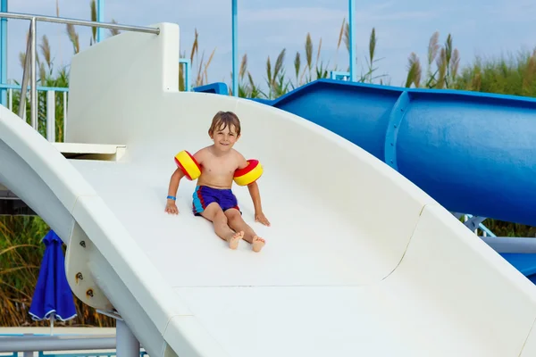 Piccolo ragazzo divertirsi sulla piscina scivolo — Foto Stock