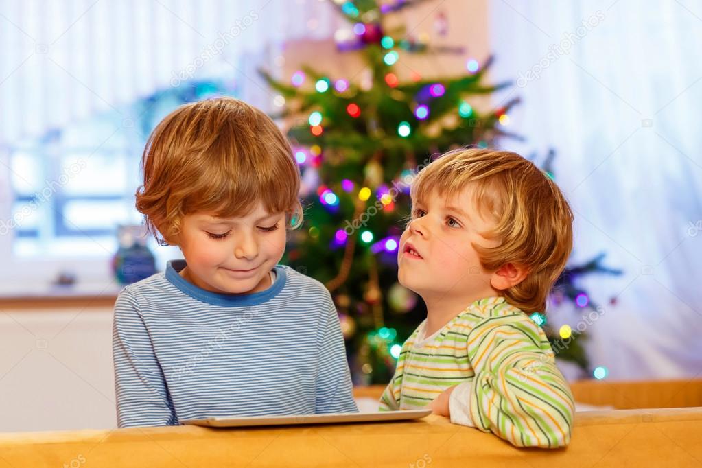 Two happy little kids playing with tablet pc, indoors