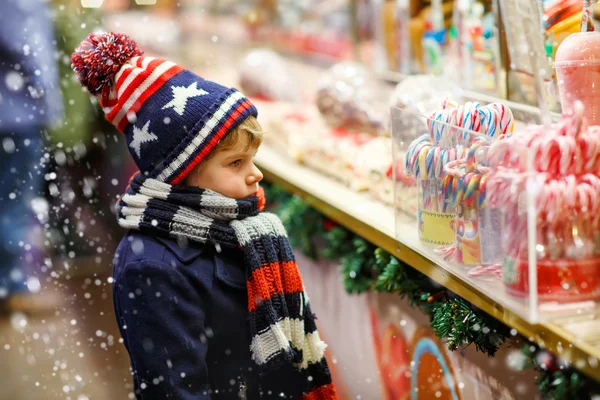 Niño pequeño con soporte de bastón de caramelo en el mercado de Navidad — Foto de Stock