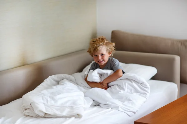 Милый мальчик после того, как спал в белой кровати с игрушкой — стоковое фото