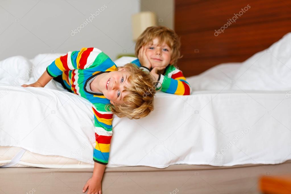 Two little sibling kid boys having fun in bed after sleeping