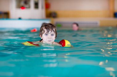 küçük çocuk çocuk swimmies bir kapalı havuzda yüzmek için öğrenme ile