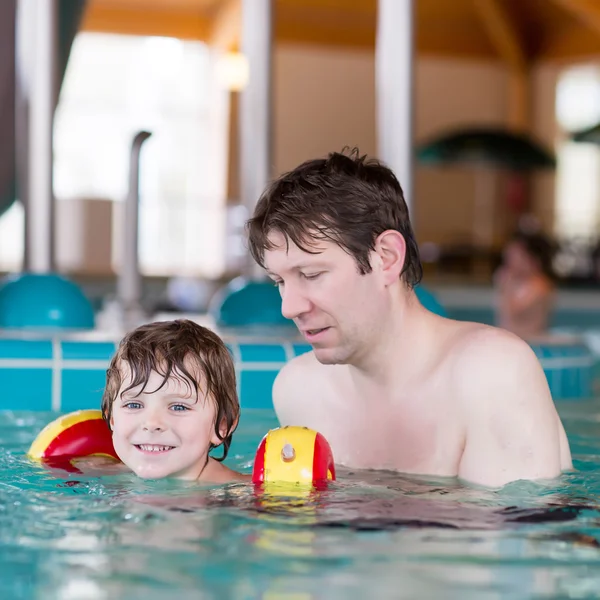 Милый маленький мальчик и его отец веселятся в бассейне — стоковое фото