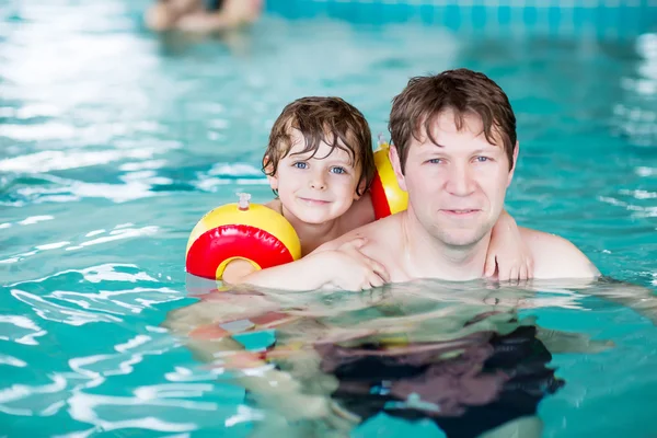 Jonge vader onderwijs zijn zoontje te zwemmen binnenshuis — Stockfoto