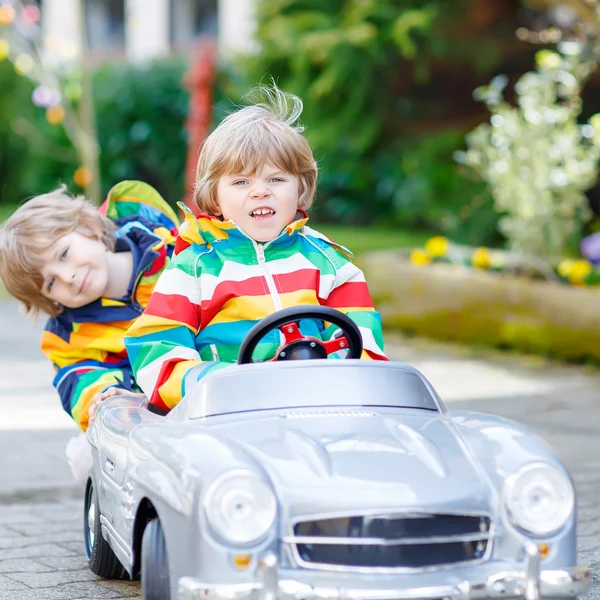 Deux garçons heureux frères et sœurs jouant avec une grande vieille voiture jouet — Photo