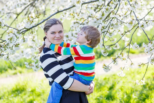 Ung mamma och Lille unge pojken i blommande trädgård — Stockfoto