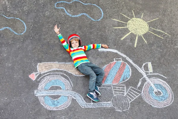 Klein kind in helm met motorfiets afbeelding tekenen met colo — Stockfoto
