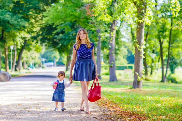 mother and her little daughter walking in summer park
