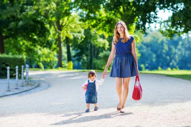 mother and her little daughter walking in summer park