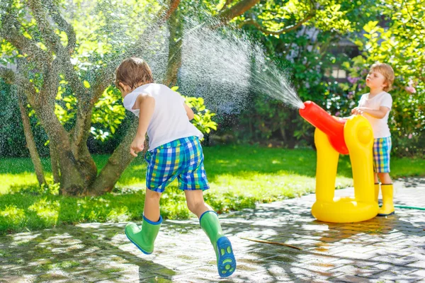 Dos niños pequeños jugando con manguera de jardín y agua en verano — Foto de Stock