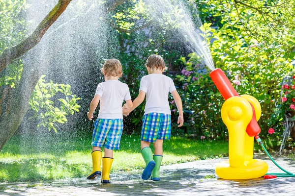 Due bambini piccoli che giocano con il tubo da giardino in estate — Foto Stock