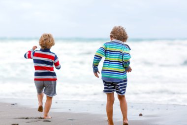 Two kid boys playing on beach on stormy day