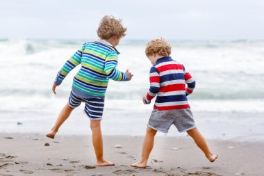 Two kid boys playing on beach on stormy day