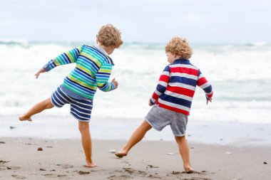 Two kid boys playing on beach on stormy day