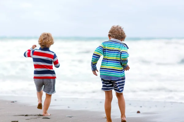 Two kid boys playing on beach on stormy day — Stock Photo, Image