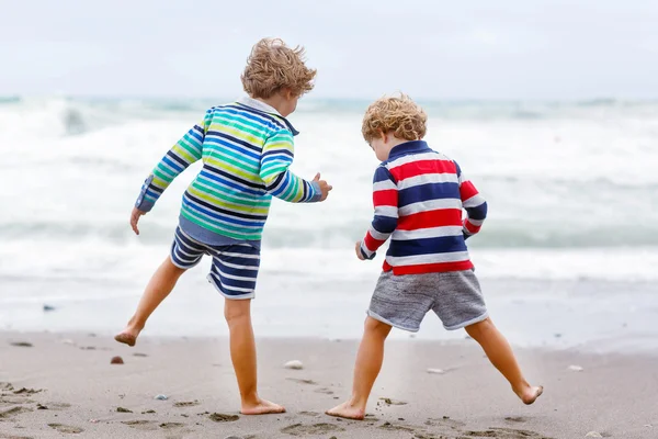 Two kid boys playing on beach on stormy day — Zdjęcie stockowe