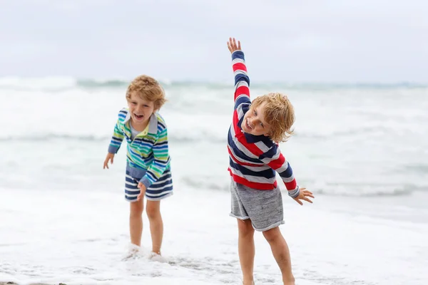 Two kid boys playing on beach on stormy day — Zdjęcie stockowe