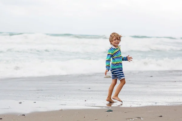 Petit garçon jouant sur la plage le jour orageux — Photo