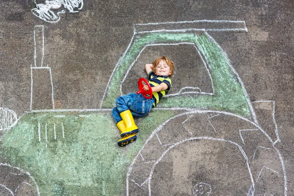 Мальчик веселится с рисунком трактора мелом — стоковое фото