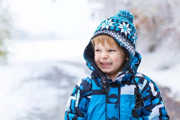 Счастливый ребенок, веселящийся со снегом зимой — стоковое фото