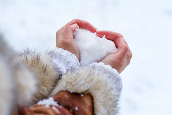 Mains de femme avec coeur de neige — Photo