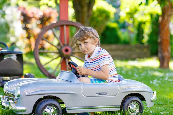 Мальчик за рулем с большой игрушечной машиной на открытом воздухе — стоковое фото