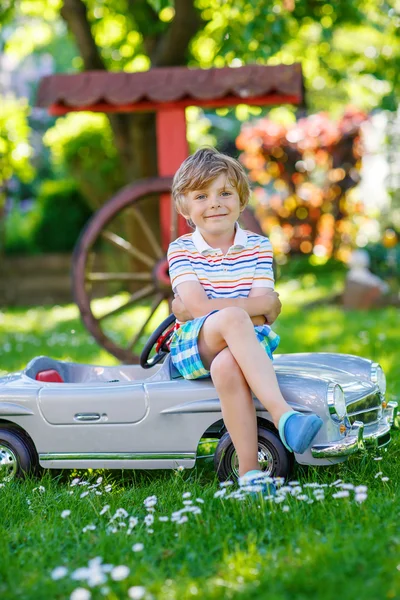 Kid boy dirigindo com grande carro de brinquedo ao ar livre — Fotografia de Stock