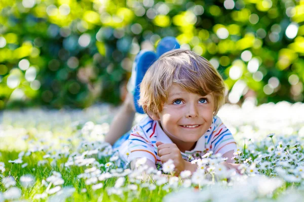 Funny kid boy laying on green grass in summer — Zdjęcie stockowe