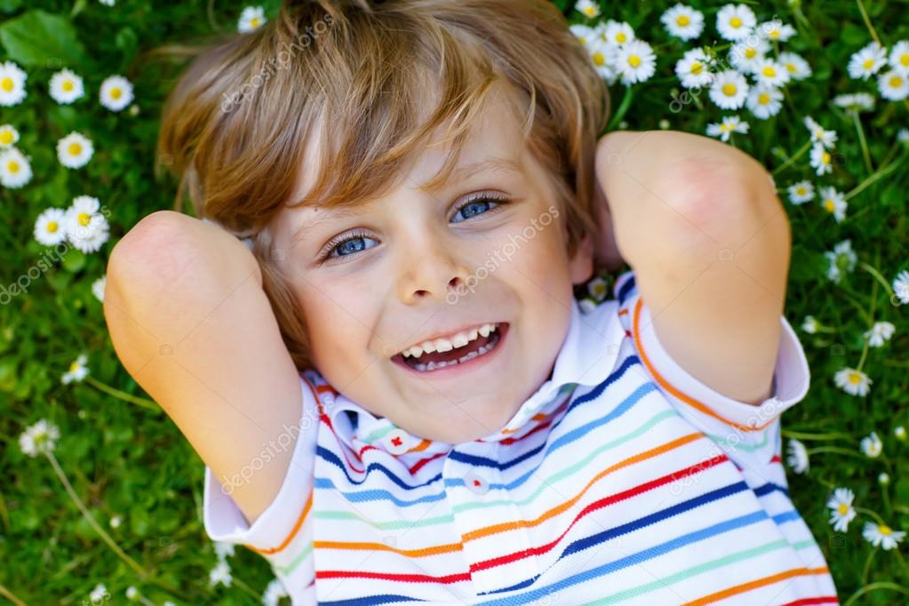 Cute Kid Boy Laying On Green Grass In Summer Stock Photo