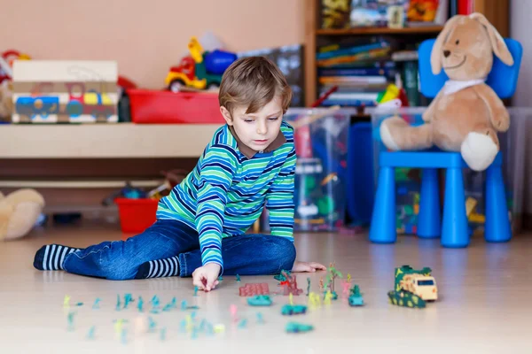 Garoto brincando com soldados de brinquedo dentro de casa no berçário — Fotografia de Stock