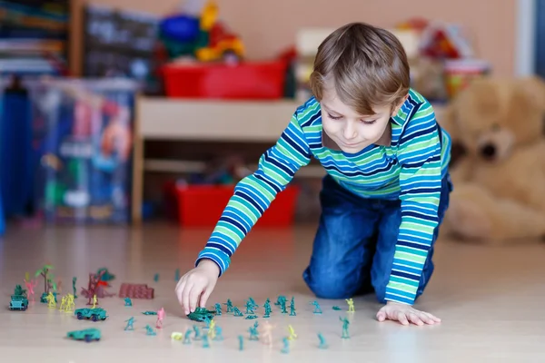 Garoto brincando com soldados de brinquedo dentro de casa no berçário — Fotografia de Stock