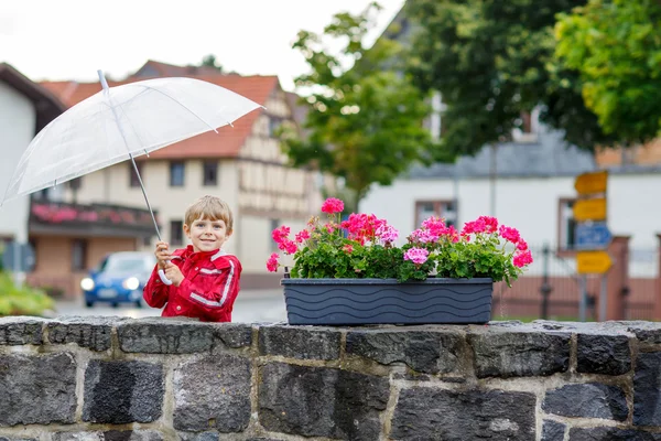 Pequeño niño rubio con gran paraguas al aire libre —  Fotos de Stock