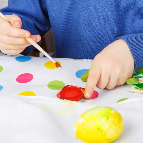 Manos de niño pintando huevos de colores para la caza de Pascua — Foto de Stock