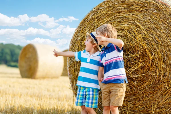 Two little children and friends with hay stack or bale — Stock Photo, Image