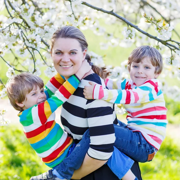 Jeune mère et deux petits jumeaux garçons avoir du plaisir dans la floraison ga — Photo