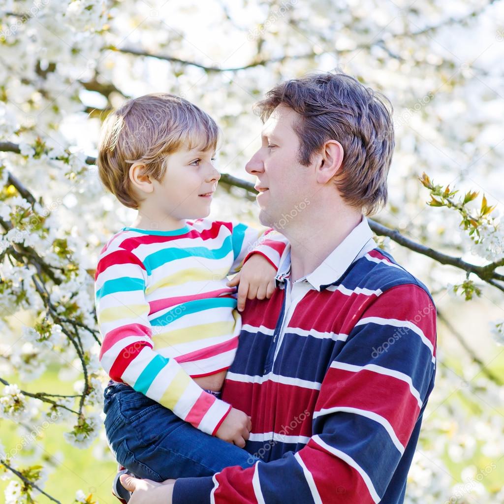 Young father and little kid boy in blooming garden
