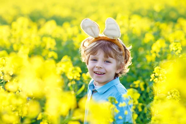 Little kid boy with Easter bunny ears in rape field — Stock Photo, Image