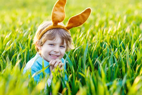 Menino adorável com orelhas de coelho de Páscoa jogando em gras verde — Fotografia de Stock