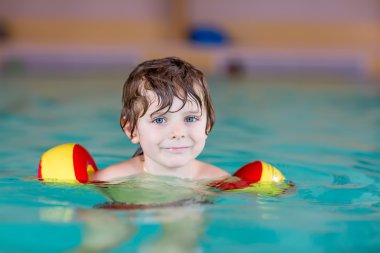 küçük çocuk çocuk swimmies bir kapalı havuzda yüzmek için öğrenme ile