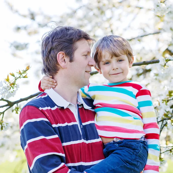 Unga far och Lille unge pojken i blommande trädgård — Stockfoto