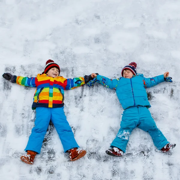 Twee jongens maken engel van de sneeuw in de winter buiten voor de beetje gek — Stockfoto