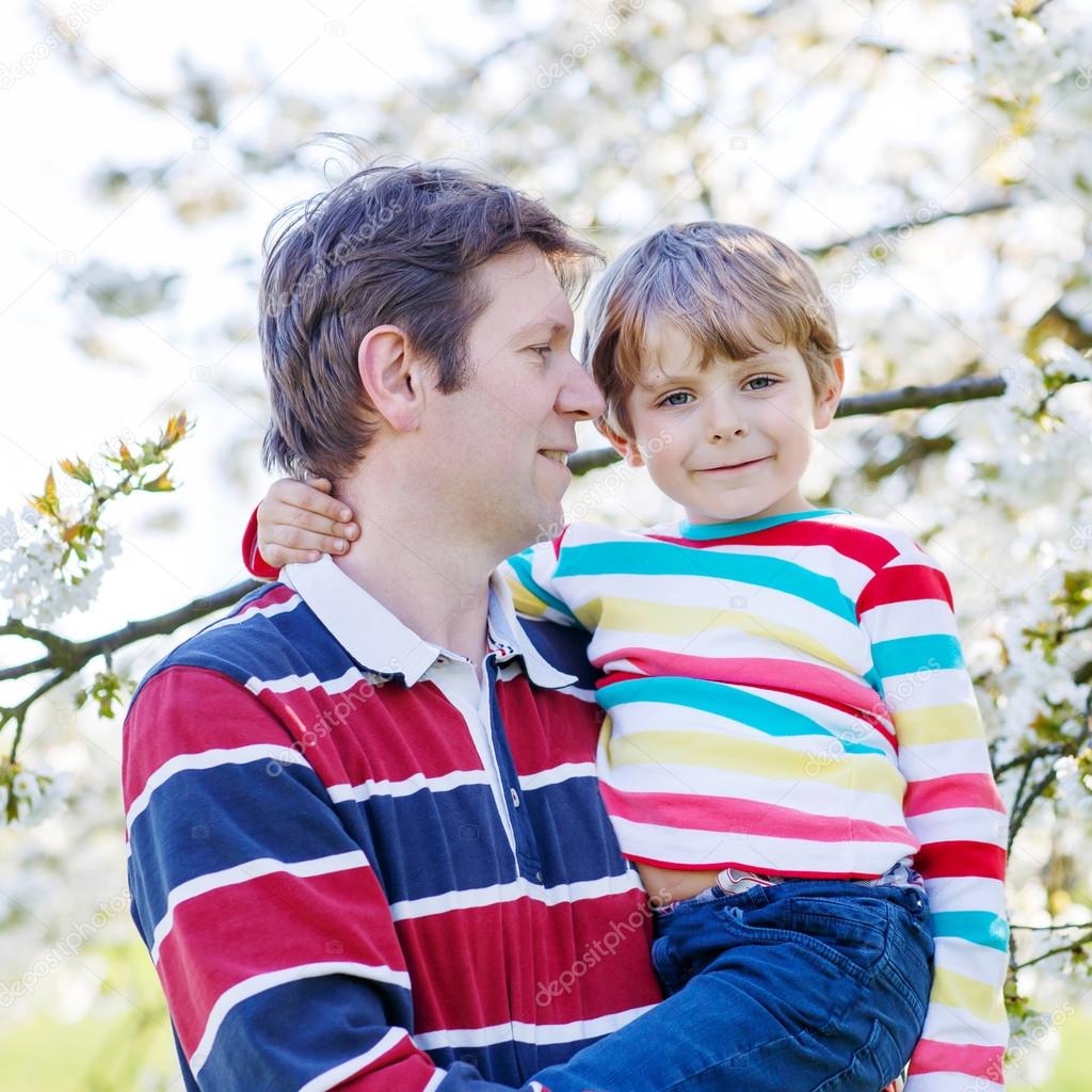 Young father and little kid boy in blooming garden